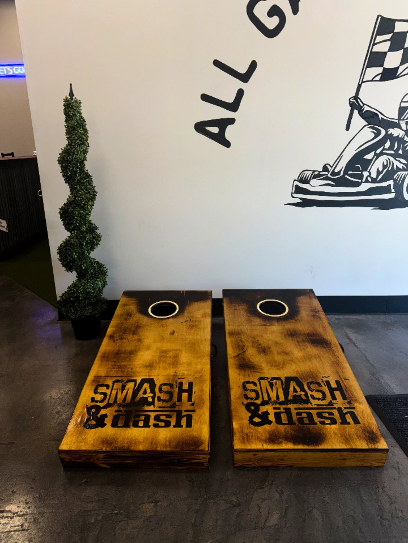 Branded cornhole boards under the go-kart mural